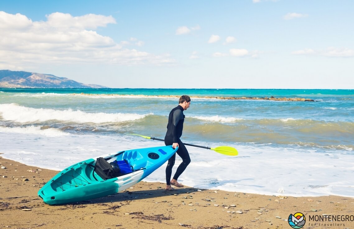 Man carrying kayak at sea beach, Budva, Montenegro